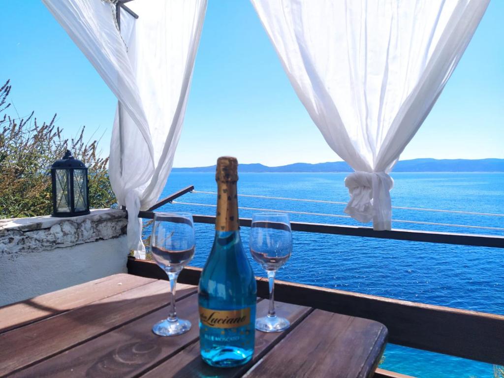 een fles wijn zittend op een tafel met twee glazen bij Old, stone 2 floor house above the sea-Najka in Pisak