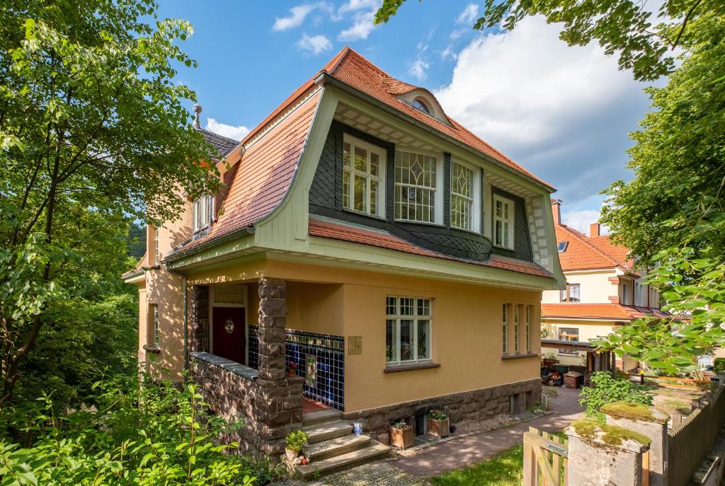 ein gelbes Haus mit rotem Dach in der Unterkunft Ferienwohnung VILLA FRÜBING in Ilmenau