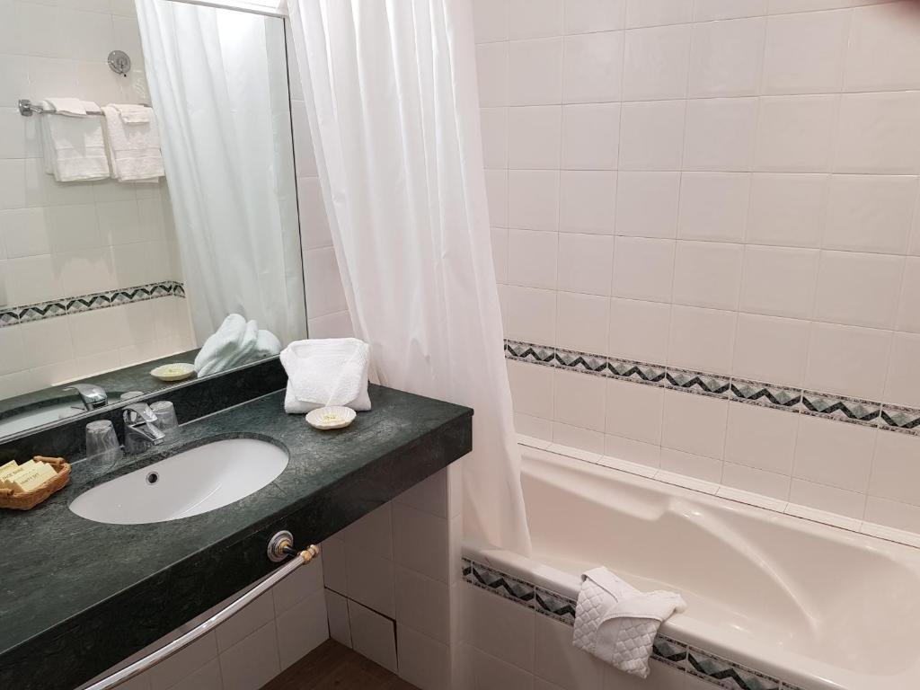 a bathroom with a sink and a bath tub at Hôtel de Charme Brise Marine in Saint-Jean-Cap-Ferrat