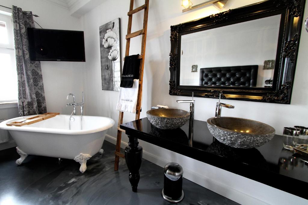 a bathroom with two sinks and a bath tub at VILLA ADELEes BOUTIQUE HOTEL in Alsfeld