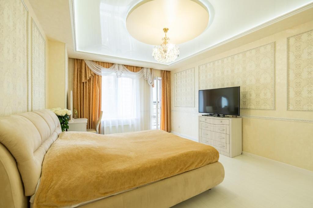 a bedroom with a large bed and a television at SC Apart Ostrovskogo 93d in Perm