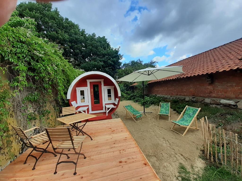 una terraza con sillas, una mesa y una sombrilla en Fuchsbau, en Walsrode