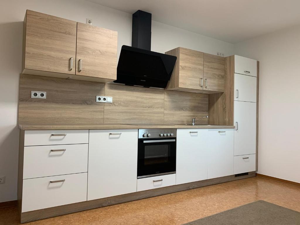 eine Küche mit weißen Schränken und einem Flachbild-TV in der Unterkunft Ferienoberwohnung in Villa Pesca in Cloppenburg