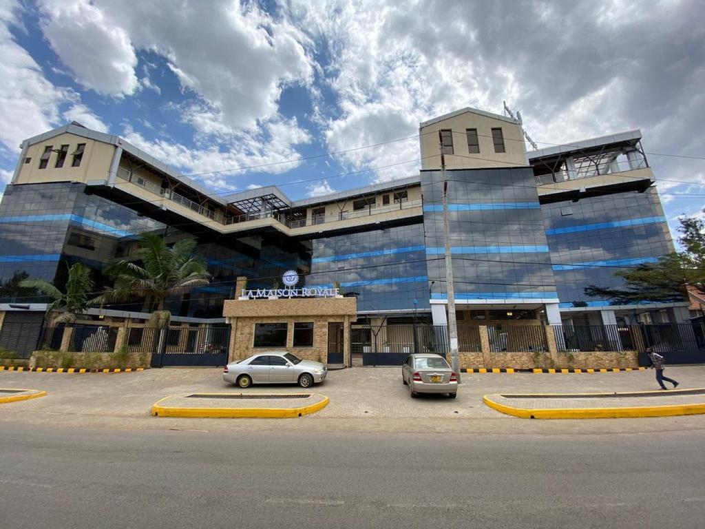 um grande edifício com carros estacionados em frente em La Maison Royale South C em Nairobi