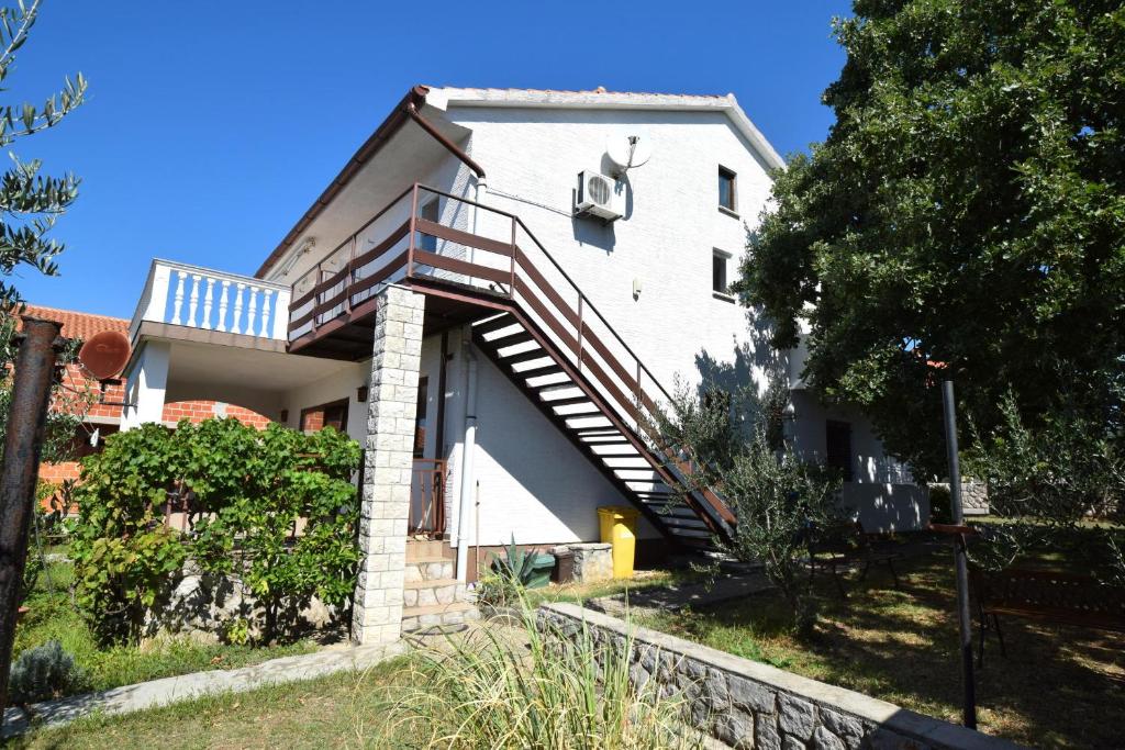 une maison blanche avec des escaliers sur son côté dans l'établissement Apartments Adriana, à Omišalj