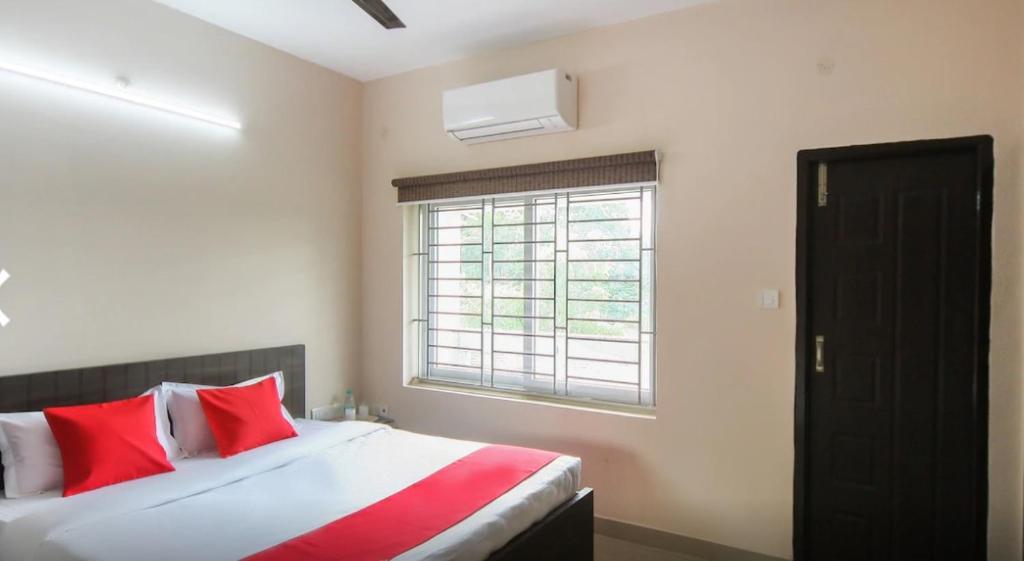 Schlafzimmer mit einem Bett mit roten Kissen und einem Fenster in der Unterkunft La Villa Beach Paradise in Mahabalipuram