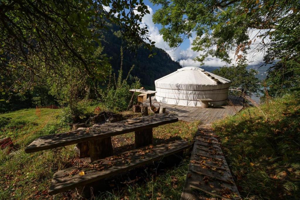 une yourte assise au sommet d'une colline avec un banc dans l'établissement Panorama Jurte Über Dem Uri-See A, à Sisikon