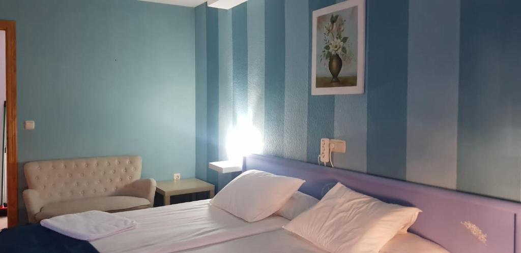 a bedroom with a white bed with a blue wall at HOTEL LOS ARENALES DE JERTE in Jerte