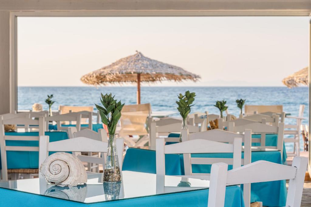 a table with chairs and an umbrella on the beach at Kokkari Beach Hotel in Kokkari