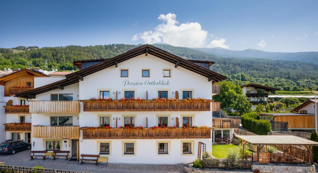 Großes weißes Gebäude mit Balkon in der Unterkunft Ferienwohnungen Ortlerblick in Mals im Vinschgau