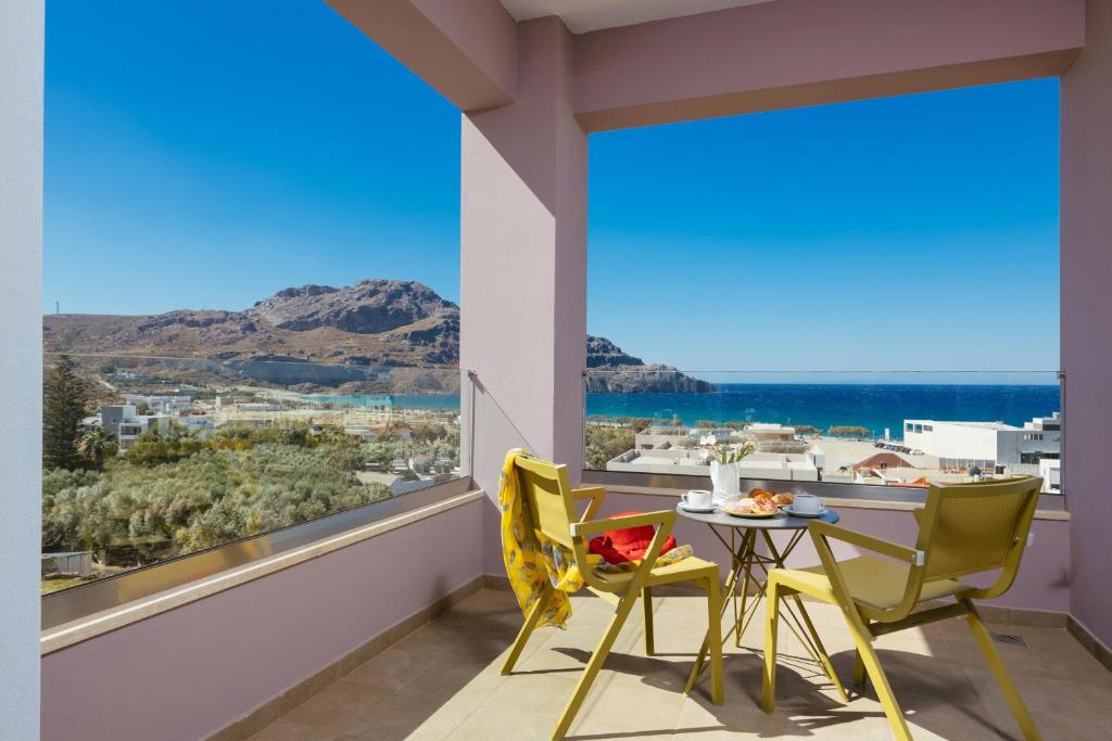 einen Balkon mit einem Tisch und Stühlen sowie einem großen Fenster in der Unterkunft Sea View Luxury Apartments in Plakias