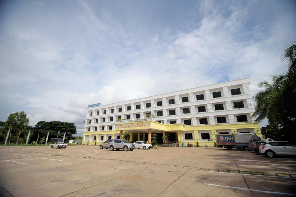 un grand bâtiment blanc avec des voitures garées dans un parking dans l'établissement Kim Jek Cin 2 Hotel - โรงแรมกิมเจ็กซิน2, à Mukdahan