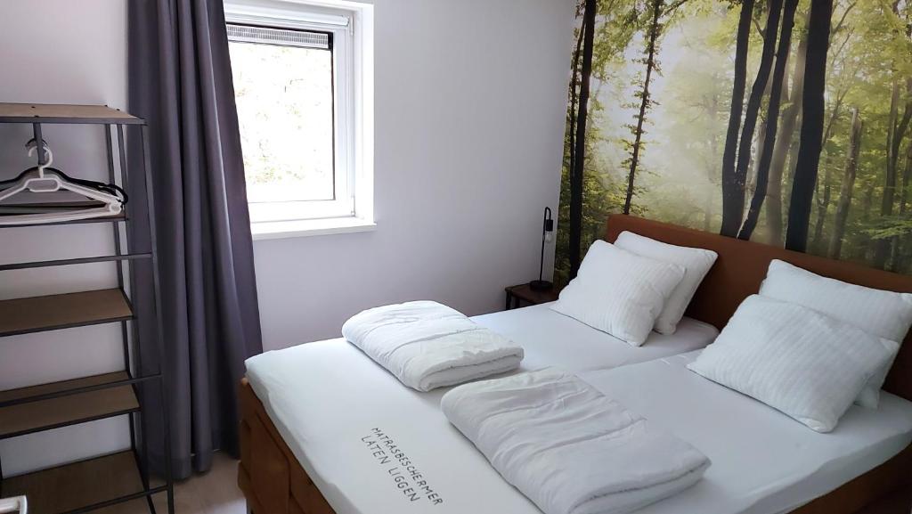 1 dormitorio con 2 camas con almohadas blancas y ventana en 't Edelhert, en Nunspeet