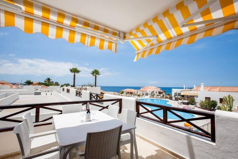 a balcony with tables and chairs and the ocean at 2 Bedroom apartment for 4 people in Tenerife in Adeje