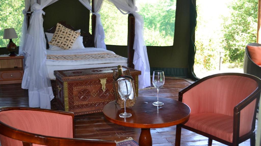 1 Schlafzimmer mit einem Bett mit einem Tisch und 2 Stühlen in der Unterkunft Osero Lodge in Ololaimutiek