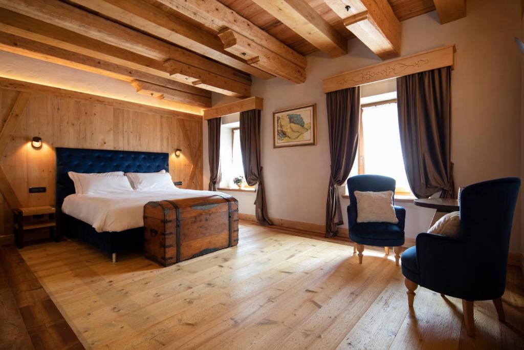a hotel room with a bed and two chairs at Al Capriolo in Vodo Cadore
