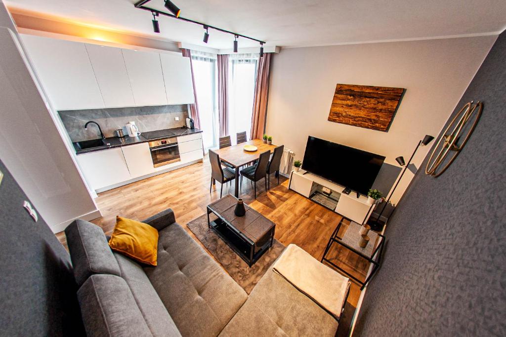a living room with a couch and a table and a kitchen at Euro Apartments New Gardens Delux in Gdańsk