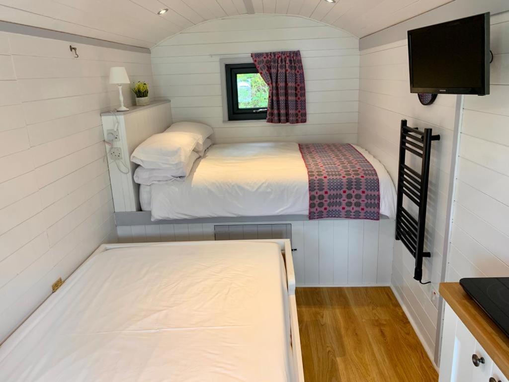 Shepherds Hut at Wern Mill في نيو كي: غرفة نوم صغيرة في منزل صغير مع سرير