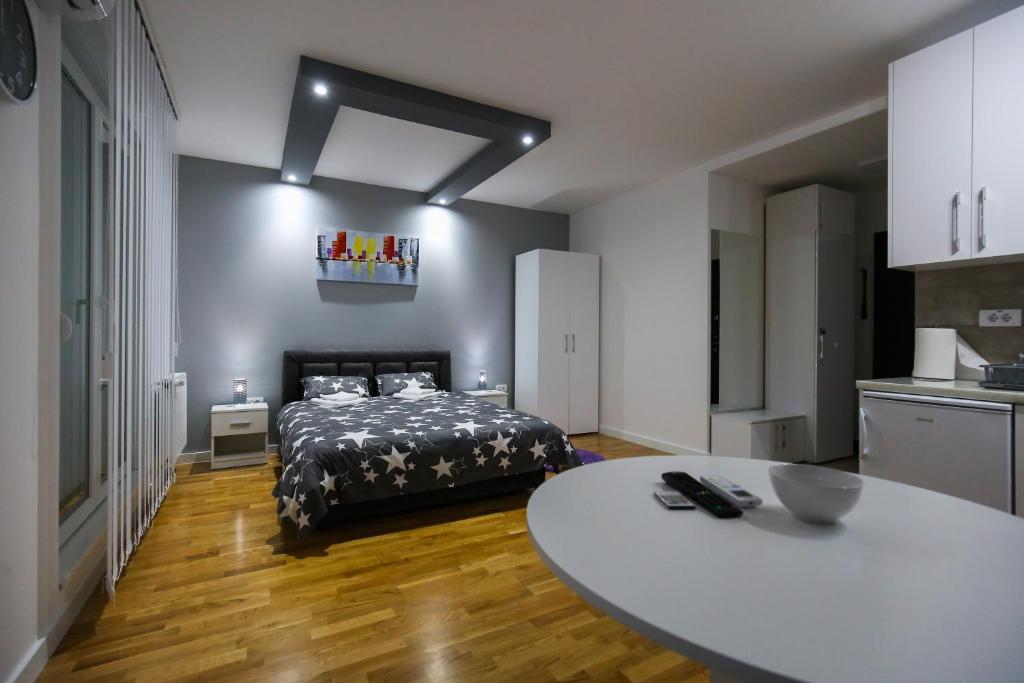 - une chambre avec un lit et une table blanche dans l'établissement MANIROSI 3 apartman, à Subotica