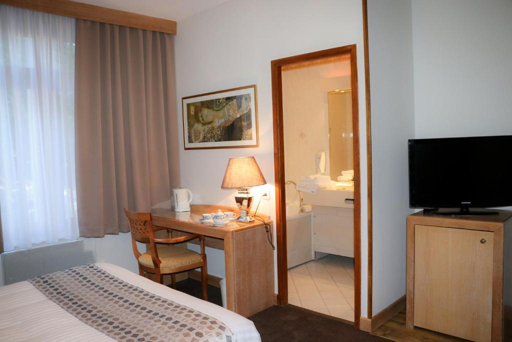 a hotel room with a bed and a desk with a television at Hotel Eden in Béthune