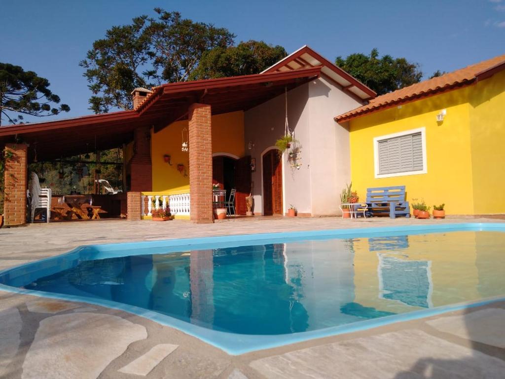 a house with a swimming pool in front of it at Chácara Recanto dos Amores in Bueno Brandão