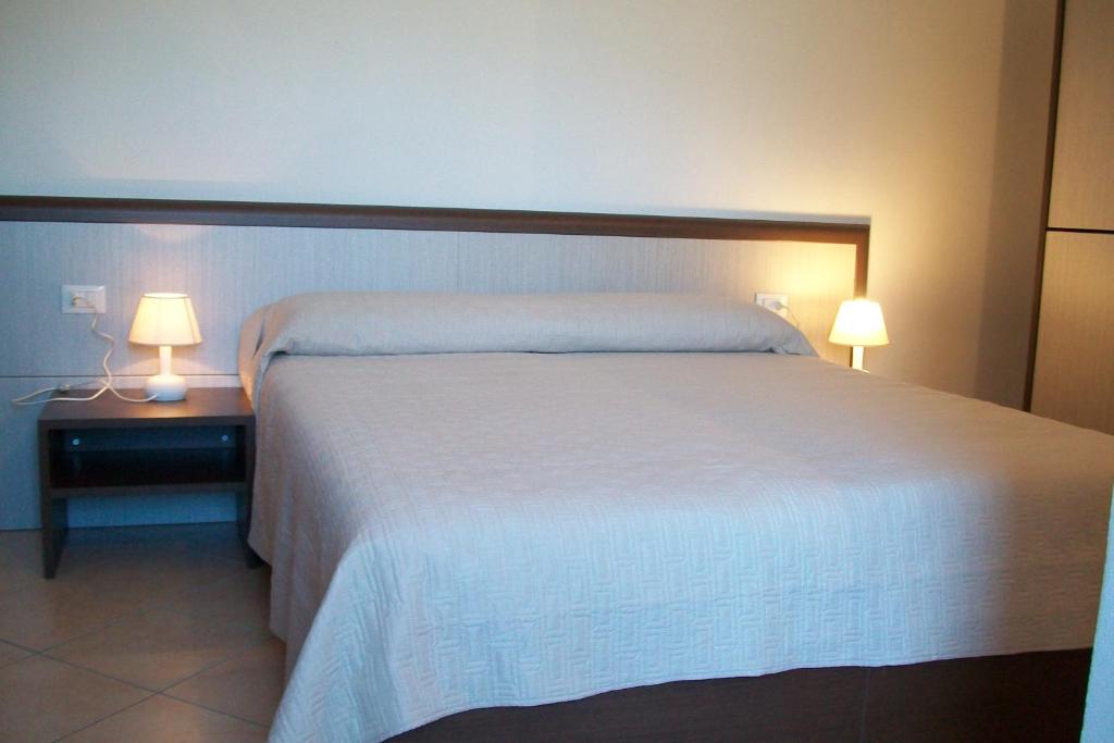 um quarto com uma cama e dois candeeiros numa mesa de cabeceira em Domo - Guest-House Il Nespolo Fiorito em Orosei