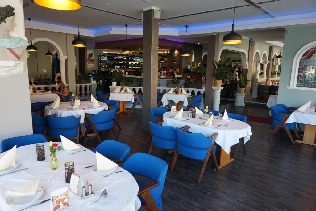 ein Restaurant mit weißen Tischen und blauen Stühlen in der Unterkunft Bone To in Salzgitter