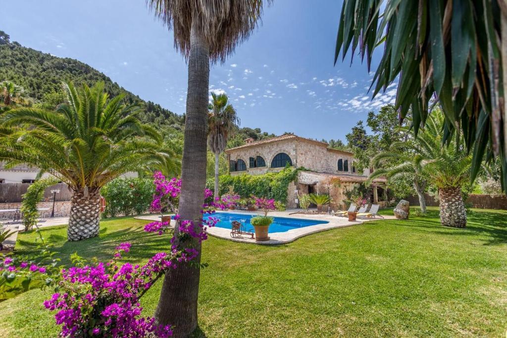 een villa met een zwembad en palmbomen bij U Coste en Pollensa in Pollença
