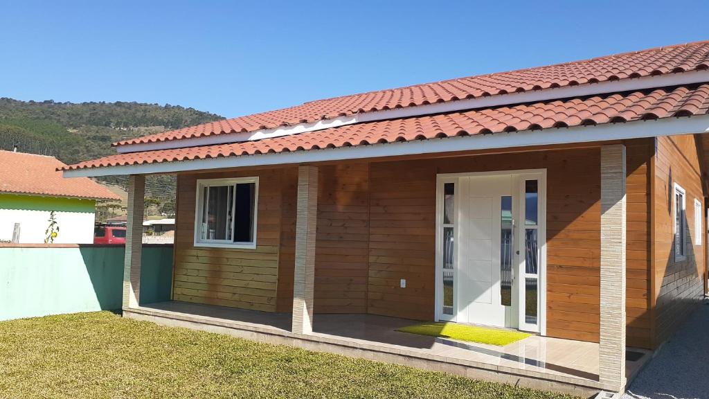 una pequeña casa de madera con techo rojo en Casas de Hospedagem Mendes, en Urubici