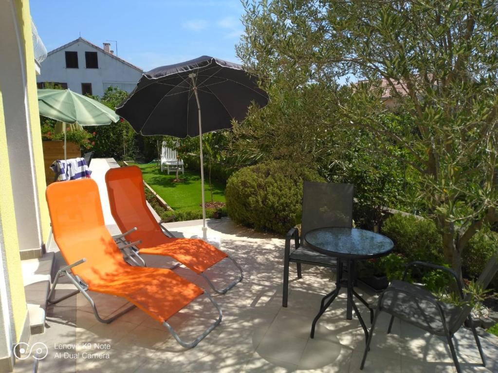 a patio with two chairs and a table with an umbrella at Ana Rooms in Krk