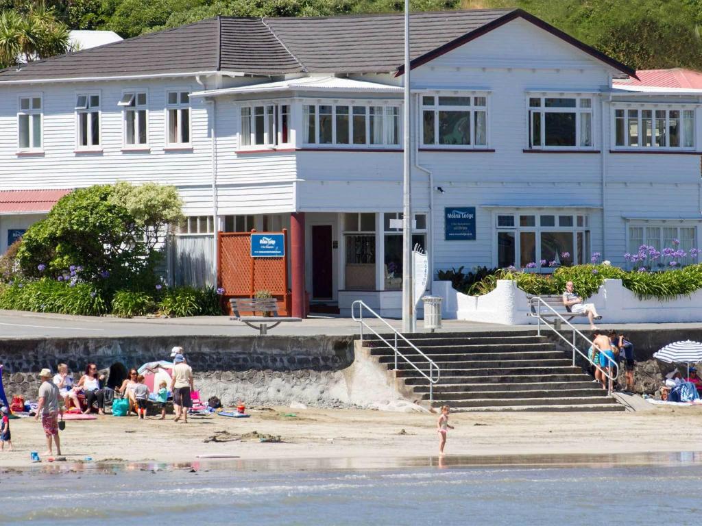 a group of people on the beach in front of a house at Moana Lodge in Plimmerton