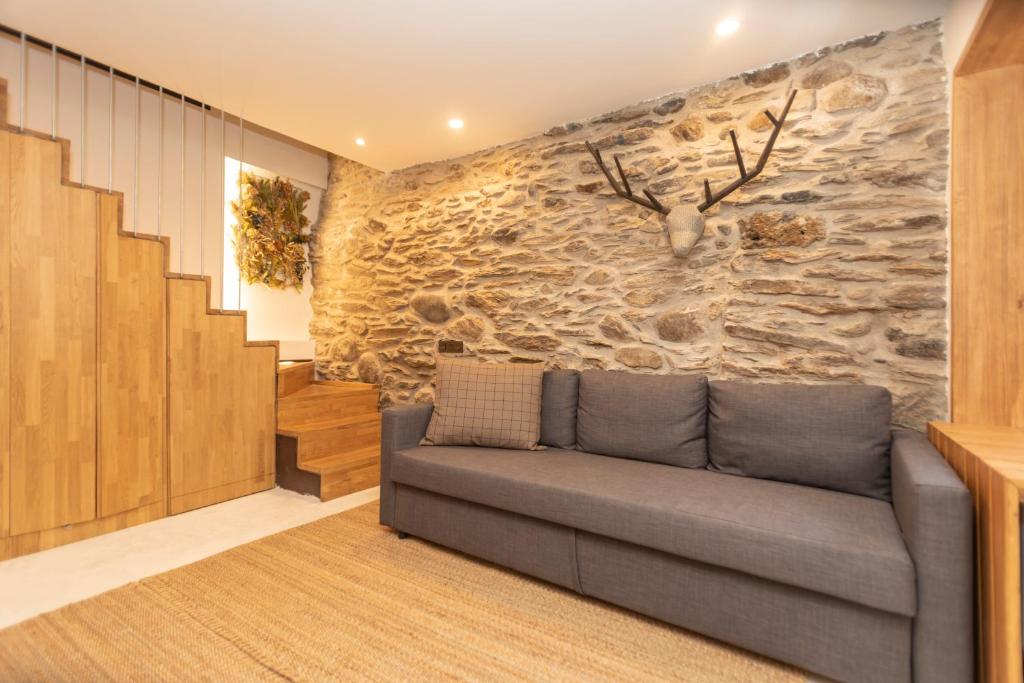ein Wohnzimmer mit einem Sofa an einer Steinmauer in der Unterkunft CASA UNCETA in Benasque