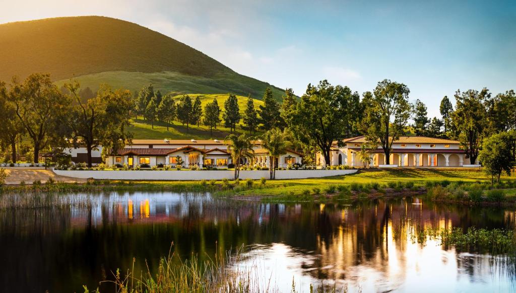 a building next to a lake with a mountain in the background at La Lomita Ranch in San Luis Obispo