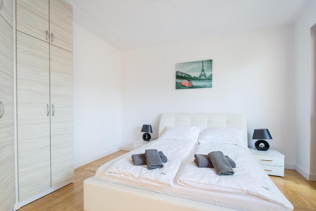 a white bedroom with a large white bed with two pillows at Apartamenty Robi in Kołobrzeg