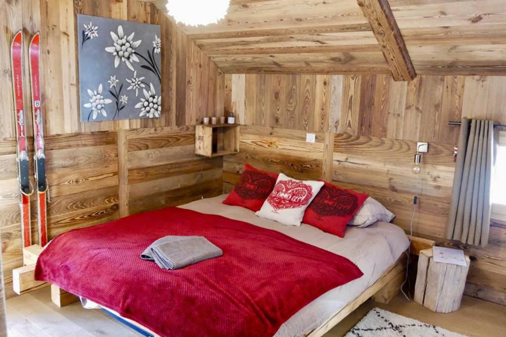 Schlafzimmer mit einem großen roten Bett mit Holzwänden in der Unterkunft chalet coup de coeur+véhicule 4*4 ; 9 places à dispo in La Clusaz