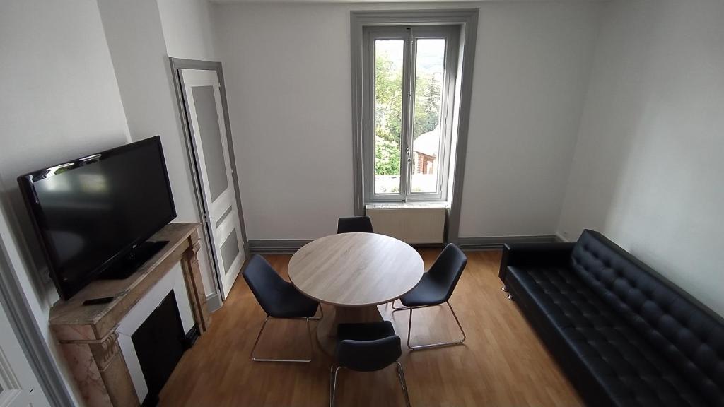 sala de estar con mesa, sillas y TV en Appart - Hotel La Batisse de Saint-Chamond, en Saint-Chamond