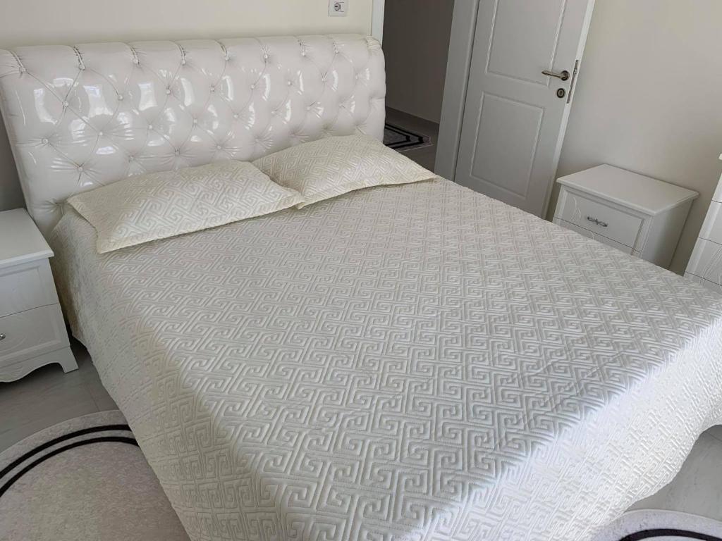 a bedroom with a white bed with a white headboard at Apartament Oresti in Korçë