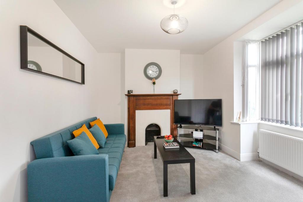 a living room with a blue couch and a fireplace at Parkdrive Hömli Place in Loughborough