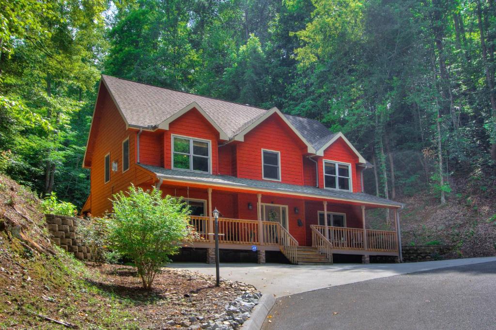 a red house in the middle of a forest at Gorgeous "Country Roads" by HoneyBearCabins 4BR 4BA, next to pool, easy drive, main strip location! in Pigeon Forge
