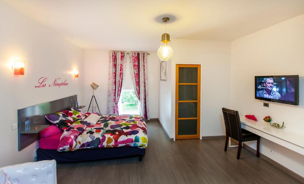 a bedroom with a bed and a desk and a television at Les étangs du moulin d'Harcy in Lonny