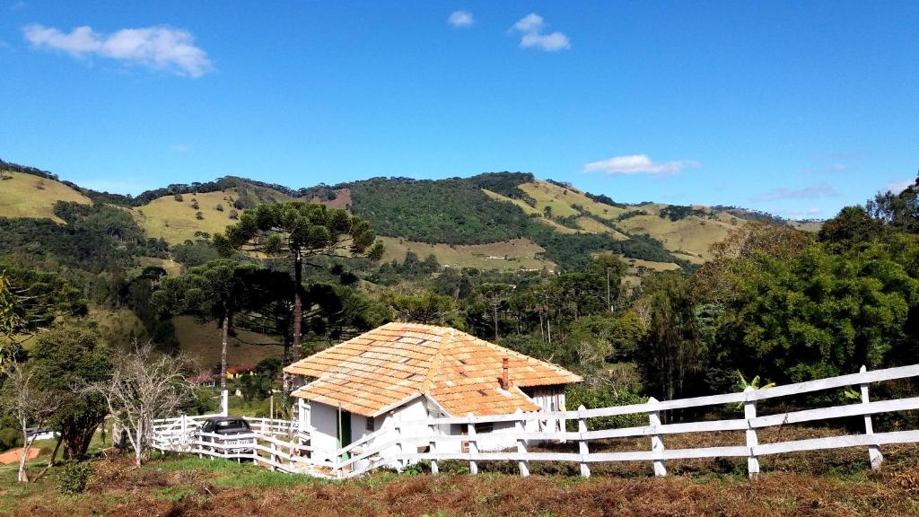 een huis met een dak op een heuvel bij Simplicidade - Uma autêntica casa de roça mineira in Delfim Moreira