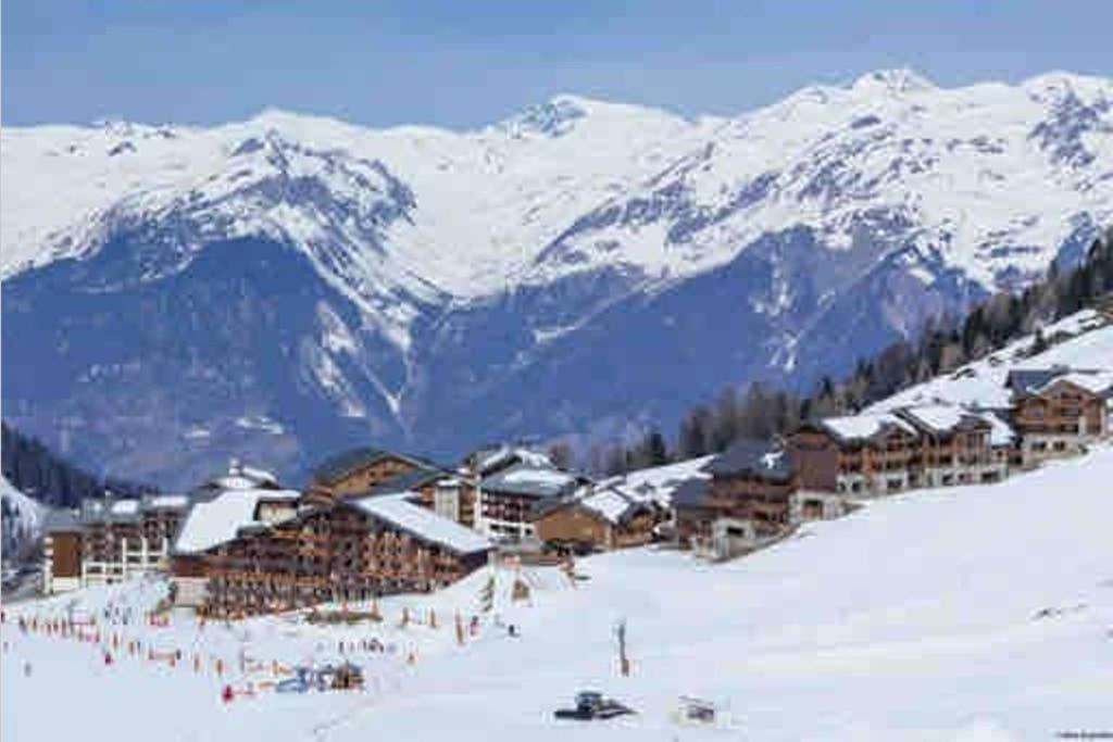 um grupo de edifícios numa pista de esqui com montanhas cobertas de neve em Appartement La Plagne soleil - Pied des pistes em Aime La Plagne