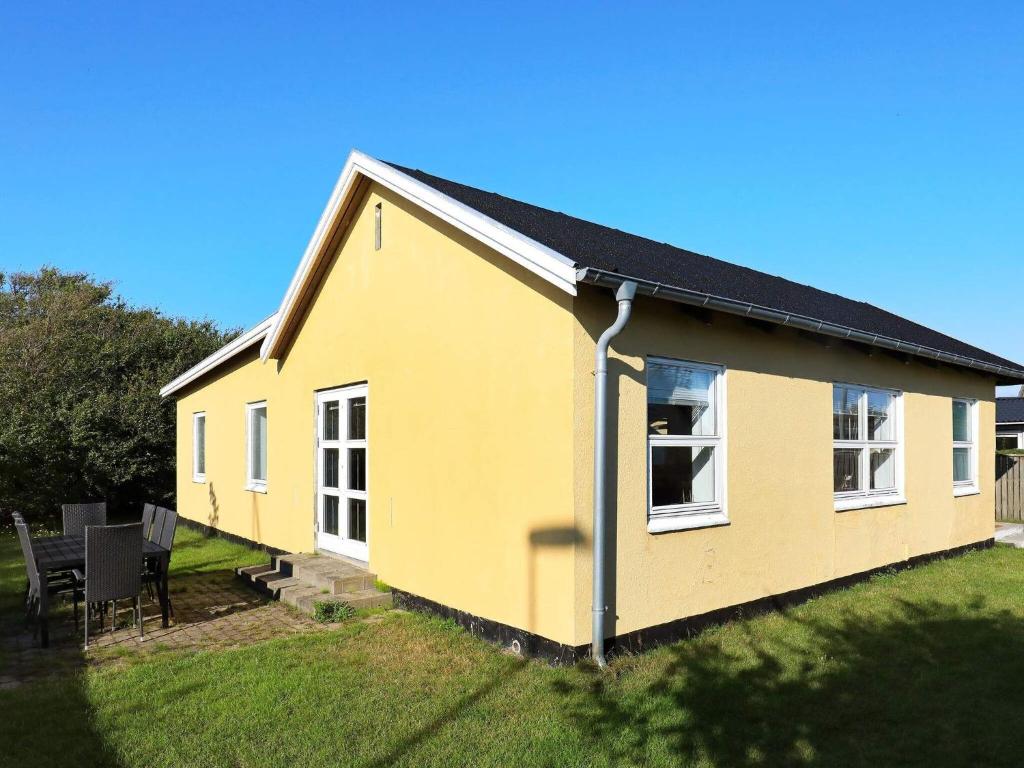 une maison jaune avec un toit noir sur une cour dans l'établissement 8 person holiday home in Skagen, à Skagen