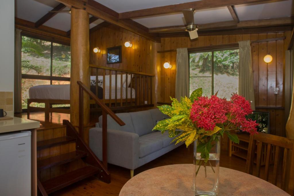 - un salon avec un canapé et un vase de fleurs sur une table dans l'établissement Milkwood Lodge, à Cooktown