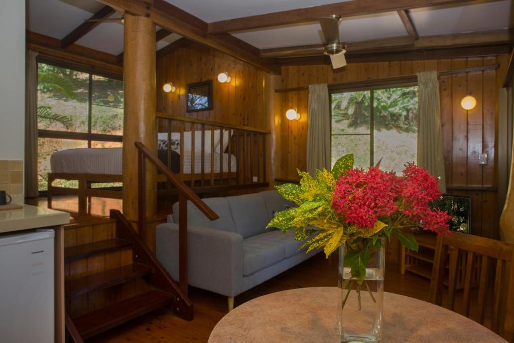 a living room with a couch and a vase of flowers on a table at Milkwood Lodge in Cooktown