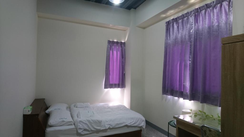 ein kleines Schlafzimmer mit lila Vorhängen und einem Bett in der Unterkunft 酵法自然環保民宿 in Houlong