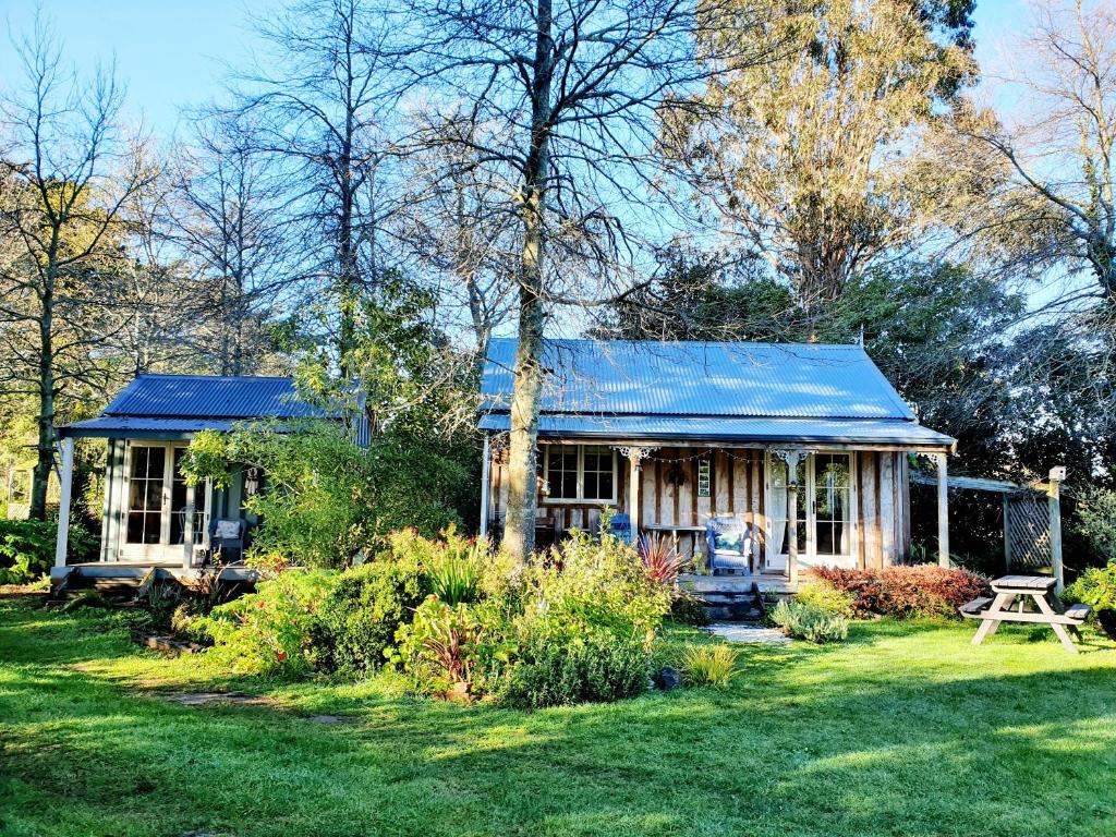 een klein huis met een blauw dak in een tuin bij Bumblebee Cottage in Greytown