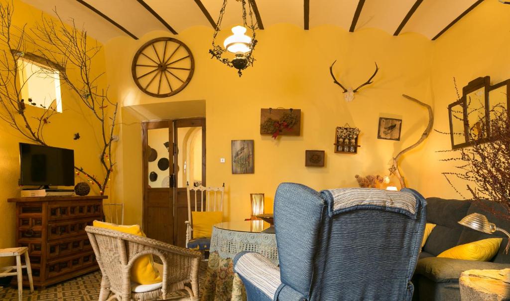 a living room with yellow walls and a couch and chairs at Casa centenaria con encanto in Zufre