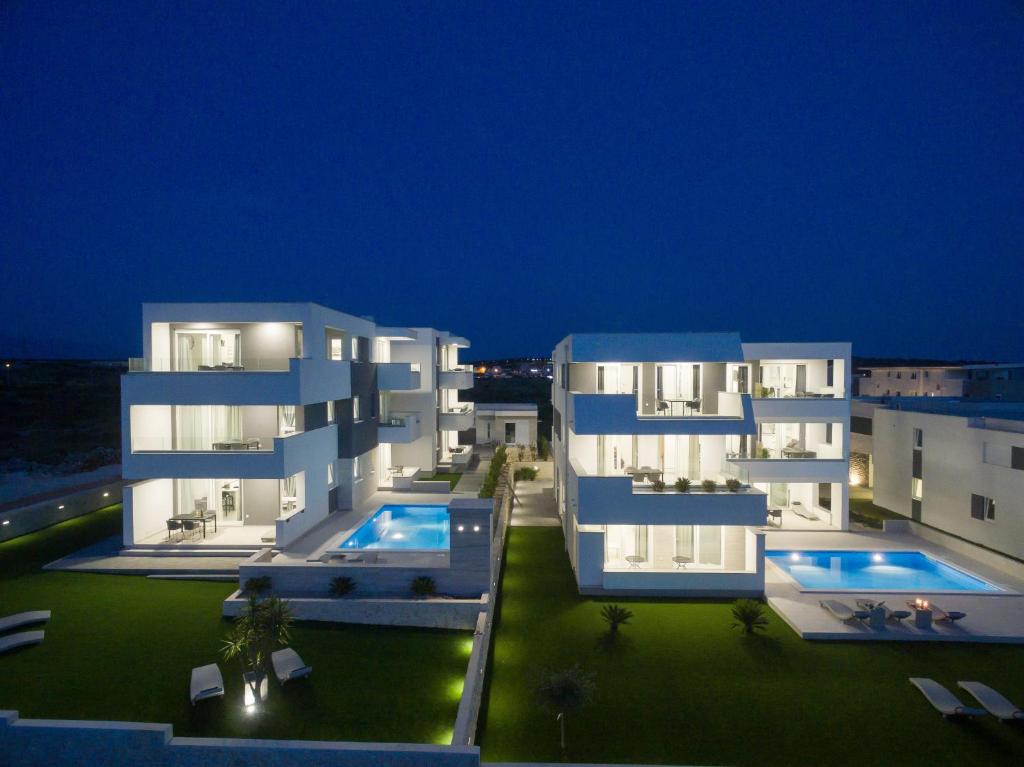 zwei weiße Apartmentgebäude mit einem Pool in der Nacht in der Unterkunft Apartments & Rooms Pool Villas Maris in Novalja