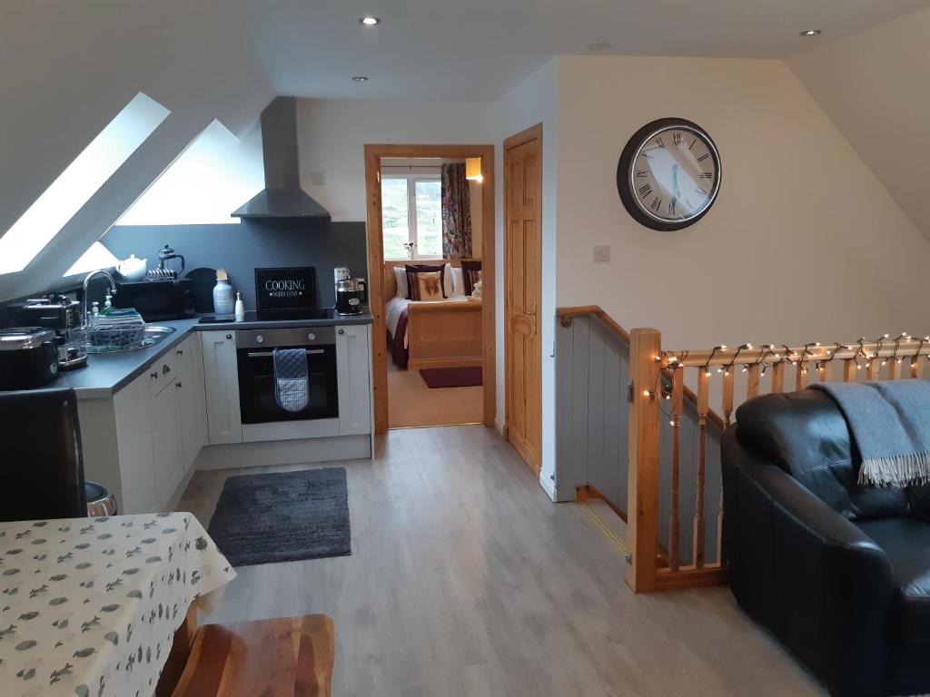 a kitchen and living room with a clock on the wall at An Cois Na H-Aibhne in Skeabost